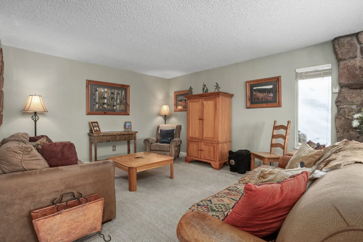 This inviting interior shows a living space with a comfortable sofa, wooden armoire, coffee table, lamps, and artwork on the walls. The mood is welcoming, suggesting a cozy retreat after a day of exploring, and the space is clearly suitable for relaxing with family or a group.